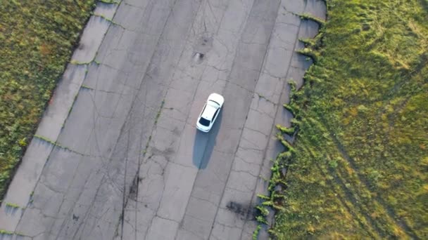 Luchtfoto van een witte auto die door een lege weg rijdt. Poltavska oblast, Oekraïne 25.07.2021 — Stockvideo