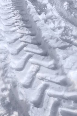 Kar yolunda araba lastiği izi sürüyor.