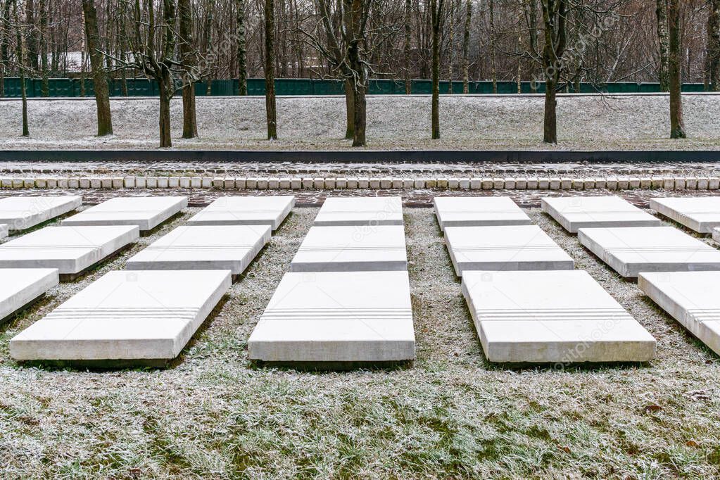 White stone slabs on mass graves of destroyed concentration camp prisoners. Memorial in memory of second world war. Winter day