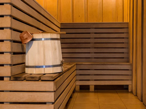 Wooden bucket with old copper ladle in steam room of sauna. Copy space