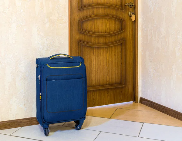 Compacte Blauwe Koffer Wielen Staat Naast Gesloten Deur Kopieerruimte — Stockfoto