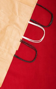 Kırmızı zemin üzerinde saplı üç Kraft kağıt geri dönüşümlü çanta var.