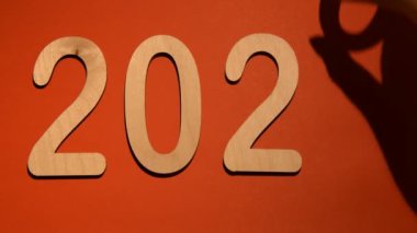 Sağ kadın eli, kırmızı arka planda 2020 'den 2021' e ahşap sıfır sayısını değiştiriyor.