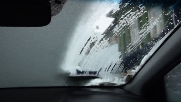 雪から手袋ブラシ車のフロントガラスの男性ドライバー 内部からの眺め — ストック動画
