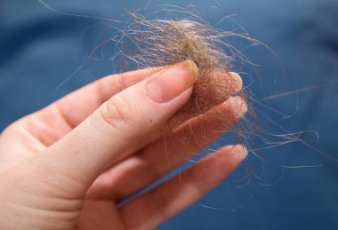 Bir kadının sol kolunda bir tutam gevşek siyah saç.