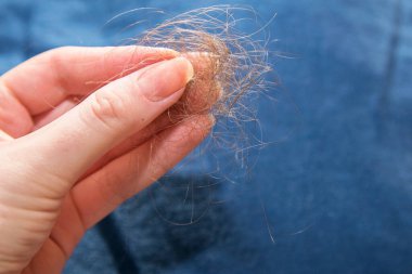 Bir kadının sol kolunda bir tutam gevşek siyah saç.