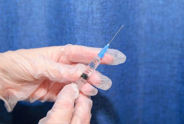 Elinde şeffaf tıbbi eldivenlerle şırıngayla iğnenin üzerine düştü.