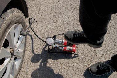 10 Nisan 2021 Rusya. Tula. Maxi alışveriş merkezinin otoparkında. Ayak pompasıyla patlak bir lastiği şişirmek