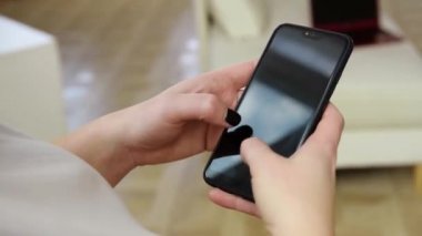 Beyaz tişörtlü bir kız telefonuna mesaj yazıyor.