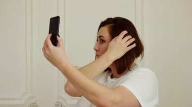 Beyaz tişörtlü esmer Avrupalı kız siyah telefonla konuşuyor.