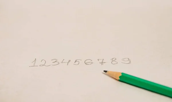 Written numbers in order from zero to nine in pencil lying side by side on a white background