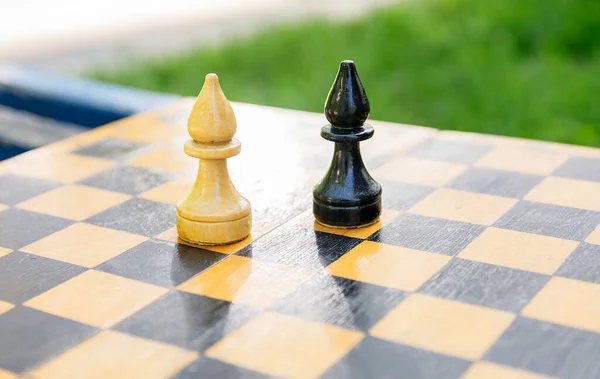 Black and white chess pieces of bishops stand on a chessboard in confrontation