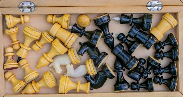 The whole set of black and white chess pieces are in the box in a different order