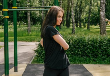 Siyahlı bir kız spor yapıyor. Spor tarafı oyun alanını açıyor.