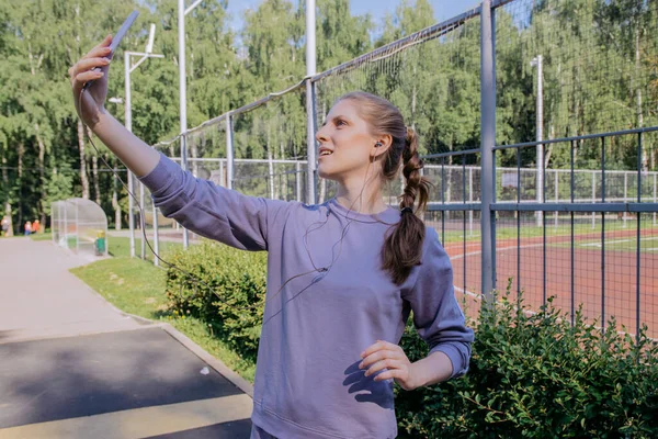 Dziewczyna Sportowym Mundurze Miejscu Treningowym Słuchawkach Telefon Rękach Robi Selfie — Zdjęcie stockowe