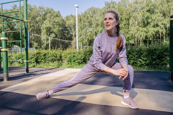 Uma Menina Fones Ouvido Uniforme Esportivo Playground Executa Estiramento Perna — Fotografia de Stock