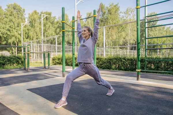 ヘッドフォンの女の子と遊び場のスポーツの制服は 足のストレッチ運動を実行します — ストック写真