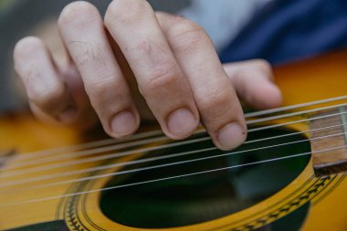 close-up of a guitar playing with the fingers of a man's hand playing the strings