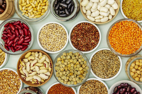 Assorted different types of beans and cereals grains. Set of indispensable sources of protein for a healthy lifestyle. Light green background, top view