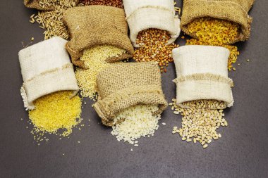 El yapımı çuvallarda çeşitli mısır gevrekleri. Sağlıklı bir diyet için gerekli malzemelerin karışımı. Siyah taş arkaplan, boşluğu kopyala