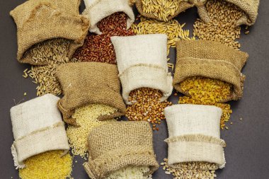 El yapımı çuvallarda çeşitli mısır gevrekleri. Sağlıklı bir diyet için gerekli malzemelerin karışımı. Siyah taş arkaplan, üst görünüm