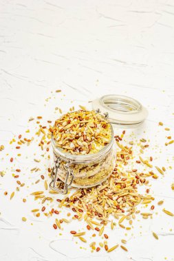 Cam kavanozda çeşitli mısır gevreklerinin karışımı. Sağlıklı bir diyet için vazgeçilmez malzemeler. Beyaz macun arkaplanı, kopyalama alanı