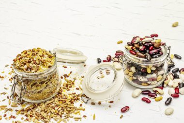 Cam kavanozlarda mısır gevreği ve fasulye karışımı. Sağlıklı bir yaşam tarzı için vazgeçilmez protein kaynakları. Beyaz macun arkaplanı, kopyalama alanı