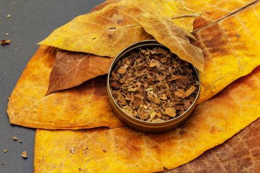 Teneke bir kutuda öğütülmüş tütün. Puro yapmak için yüksek kaliteli büyük yapraklar. Siyah taş arkaplan, üst görünüm