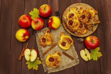Ev yapımı lezzetli elmalı tatlı. Taze fırın, porsiyonlu puf böreği. Kokulu tarçın çubukları, olgun elmalar, sonbahar yaprakları, deniz tuzu. Tahta masa, üst manzara.
