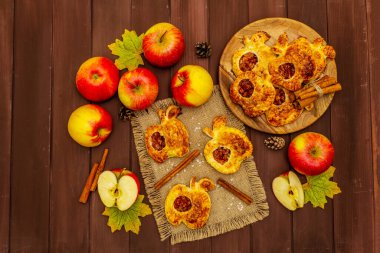 Ev yapımı lezzetli elmalı tatlı. Taze fırın, porsiyonlu puf böreği. Kokulu tarçın çubukları, olgun elmalar, sonbahar yaprakları, deniz tuzu. Tahta masa, üst manzara.