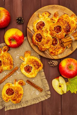 Ev yapımı lezzetli elmalı tatlı. Taze fırın, porsiyonlu puf böreği. Kokulu tarçın çubukları, olgun elmalar, sonbahar yaprakları, deniz tuzu. Tahta masa, üst manzara.