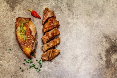 Taze biberiyeli kızarmış ördek göğsü, kuru kırmızı biber ve yeşil biber. Lezzetli yemek, dilimlenmiş et, kaba deniz tuzu. Taş beton zemin, üst görünüm