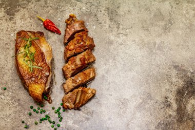 Taze biberiyeli kızarmış ördek göğsü, kuru kırmızı biber ve yeşil biber. Lezzetli yemek, dilimlenmiş et, kaba deniz tuzu. Taş beton zemin, üst görünüm