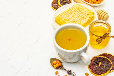 Deniz dikenli çay, vitamin ve mikroelementlerle dolu lezzetli bir aroma. Tatlım, taze böğürtlen, bal peteği ve limon. Beyaz macun arkaplanı, kopyalama alanı