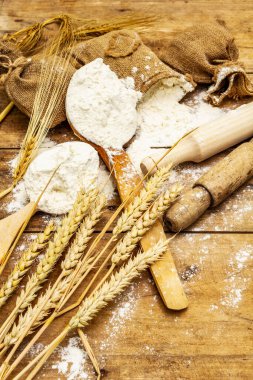 Torbalarda un, tahıl kulakları, kaşıklar ve tahta raptiyeler. Pişirme konsepti, ahşap tahta arka plan, kapat
