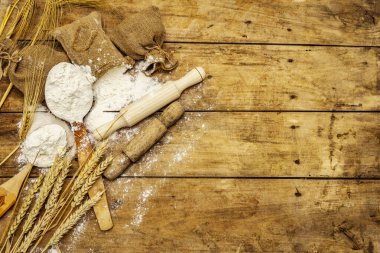 Torbalarda un, tahıl kulakları, kaşıklar ve tahta raptiyeler. Pişirme konsepti, tahta tahta arka plan, üst görünüm