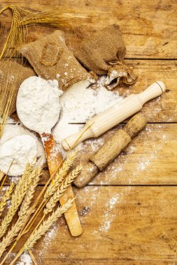 Torbalarda un, tahıl kulakları, kaşıklar ve tahta raptiyeler. Pişirme konsepti, ahşap tahta arka plan, kapat