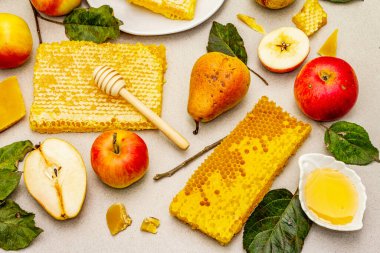 Rosh Hashanah geleneksel sembollerle kutlama konsepti. Yeni yıl Yahudi bayramında taze elmalar, armutlar, sıvı bal ve bal petekleri. Hafif taş arkaplan, üst görünüm