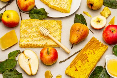 Rosh Hashanah geleneksel sembollerle kutlama konsepti. Yeni yıl Yahudi bayramında taze elmalar, armutlar, sıvı bal ve bal petekleri. Hafif taş arkaplan, üst görünüm