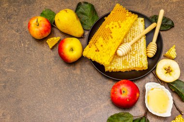 Rosh Hashanah geleneksel sembollerle kutlama konsepti. Yeni yıl Yahudi bayramında taze elmalar, armutlar, sıvı bal ve bal petekleri. Kahverengi taş arkaplan, üst görünüm
