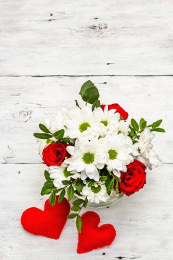 Bir buket taze çiçek ve kırmızı keçeli kalp. Sevgililer günü ya da düğün konsepti. Beyaz eski tahtalar arka plan