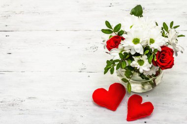 Bir buket taze çiçek ve kırmızı keçeli kalp. Sevgililer günü ya da düğün konsepti. Beyaz eski tahtalar arka plan