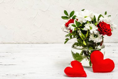 Bir buket taze çiçek ve kırmızı keçeli kalp. Sevgililer günü ya da düğün konsepti. Beyaz eski tahtalar arka plan