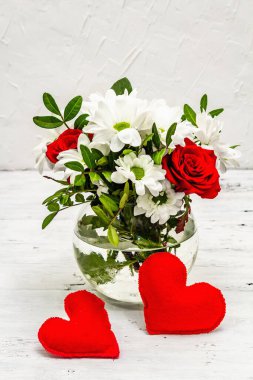 Bir buket taze çiçek ve kırmızı keçeli kalp. Sevgililer günü ya da düğün konsepti. Beyaz eski tahtalar arka plan
