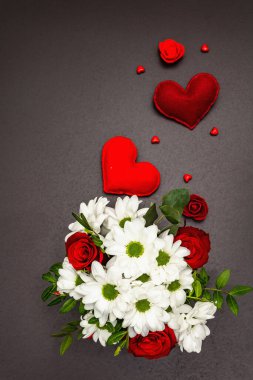 Cam vazoda bir buket taze çiçek ve yumuşak kalpler. Sevgililer günü ya da düğün konsepti. Siyah taş beton arka plan