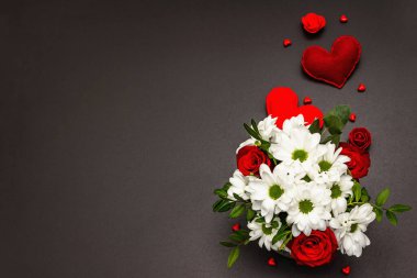 Cam vazoda bir buket taze çiçek ve yumuşak kalpler. Sevgililer günü ya da düğün konsepti. Siyah taş beton arka plan