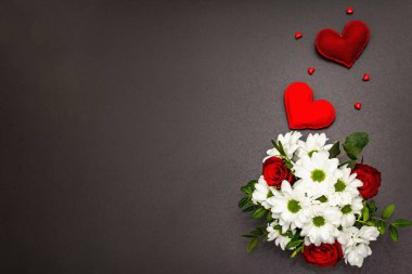 Cam vazoda bir buket taze çiçek ve yumuşak kalpler. Sevgililer günü ya da düğün konsepti. Siyah taş beton arka plan