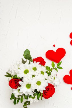Bir buket taze çiçek ve kırmızı keçeli kalp. Sevgililer günü ya da düğün konsepti. Beyaz macun arkaplanı