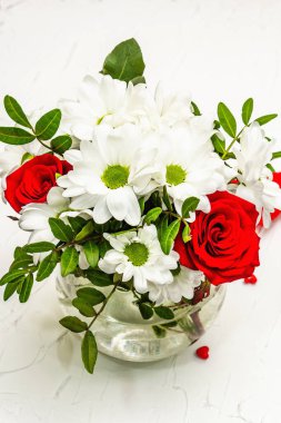 Bir buket taze çiçek ve kırmızı keçeli kalp. Sevgililer günü ya da düğün konsepti. Beyaz macun arkaplanı