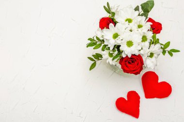 Bir buket taze çiçek ve kırmızı keçeli kalp. Sevgililer günü ya da düğün konsepti. Beyaz macun arkaplanı